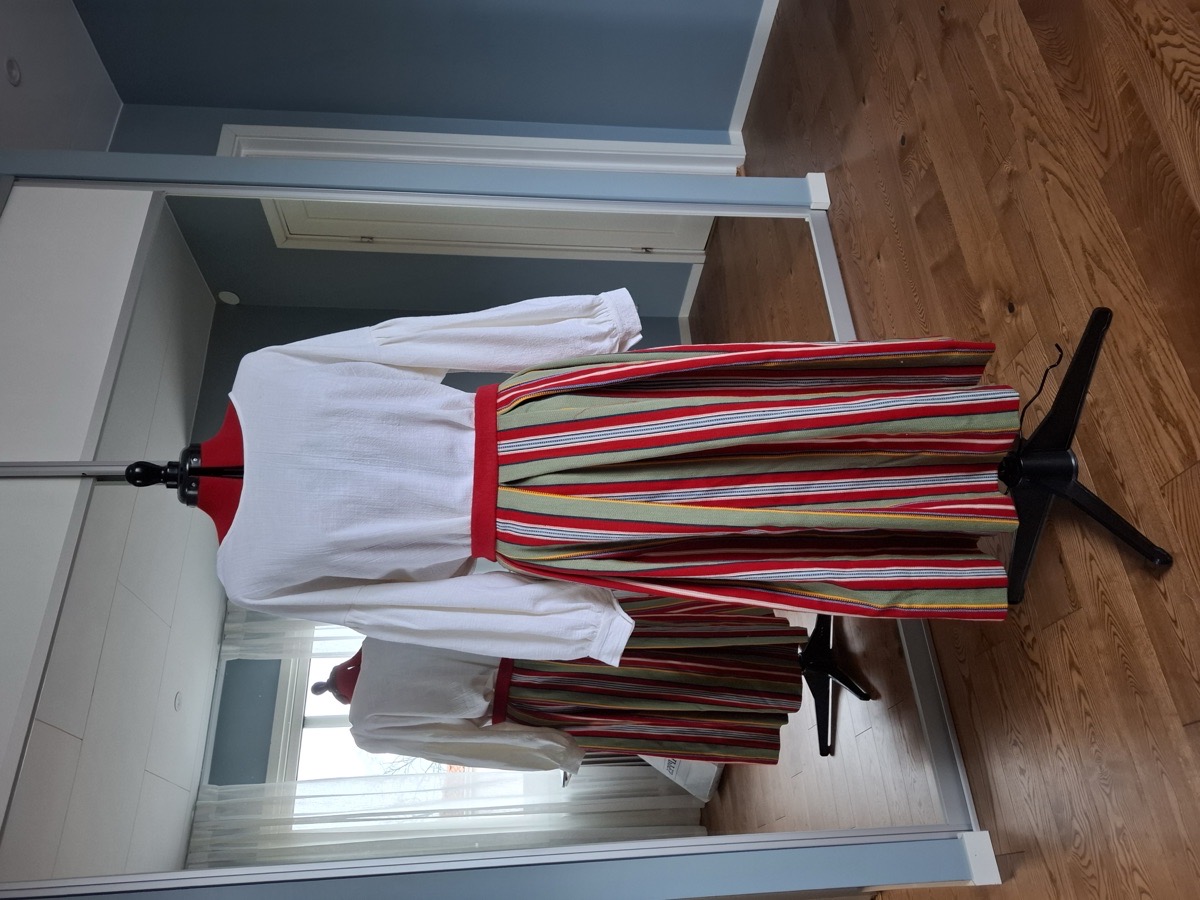 Randig folkdräktskjol med vit blus på provdocka